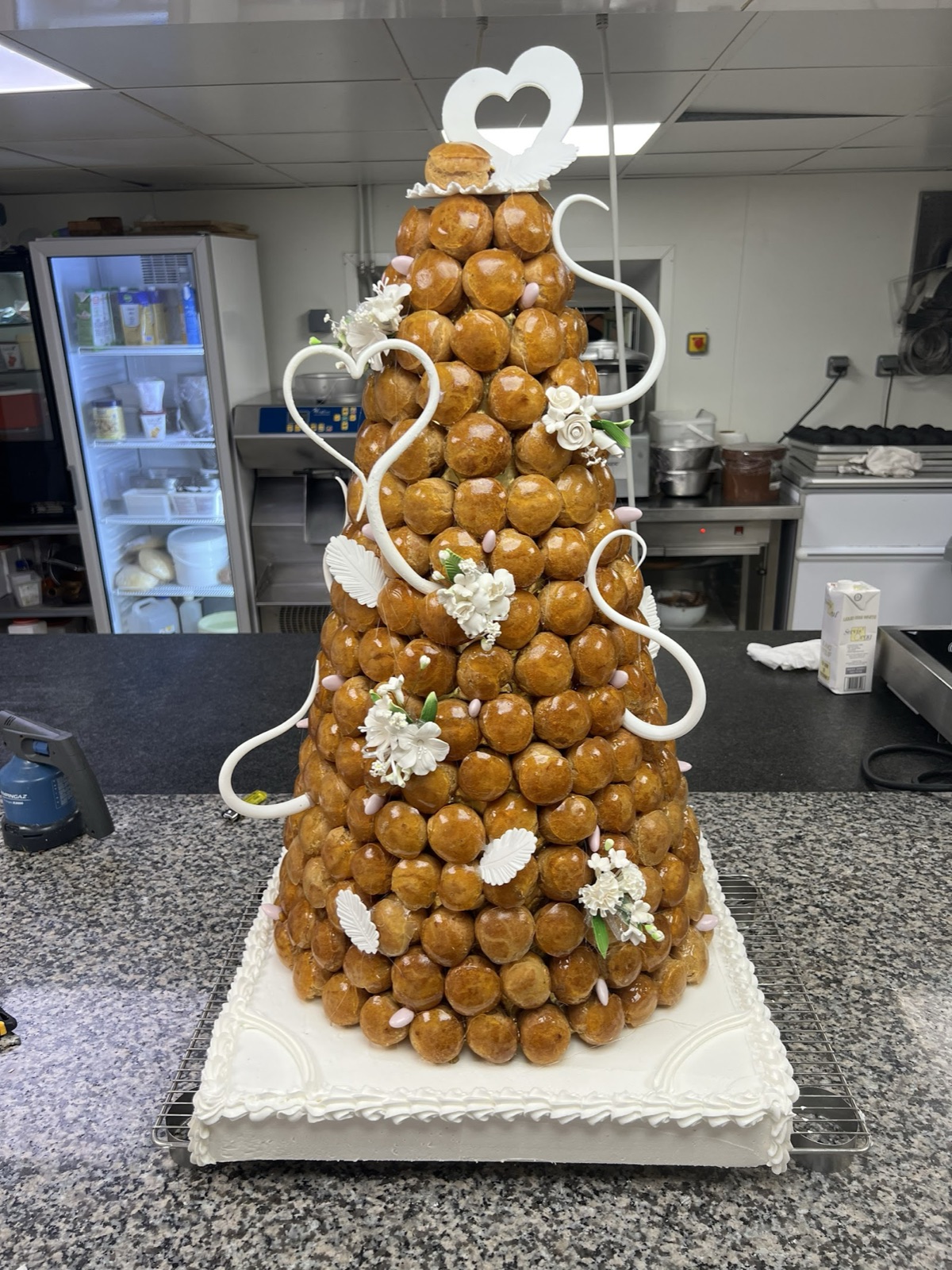 Pièce montée de choux caramélisés décorée de fleurs, réalisée dans notre atelier